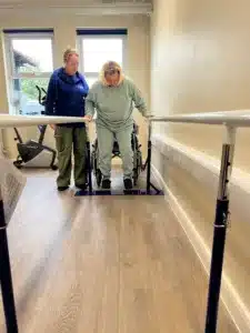 Paul's Place member, Rebecca Foreman, using the Parallel bars with Support Worker, Maria's, help. 