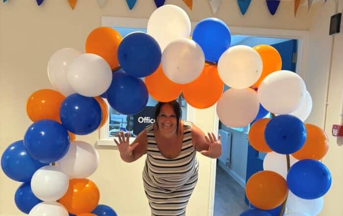 Trustee, Nicole Beebee surrounded by white, blue and orange balloons.