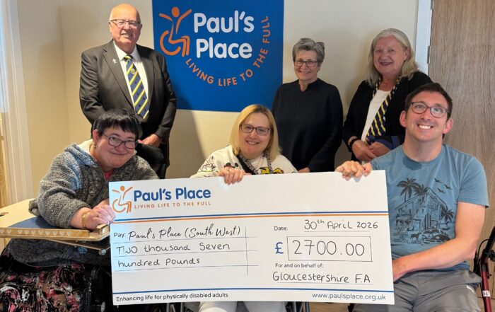 Two members from the Football club presenting a large cheque to Lynda, CEO, and three Paul's Place members